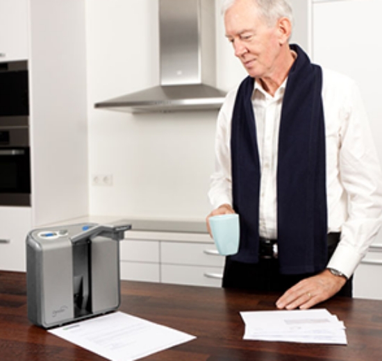 Mann mit Vorlesegerät lässt sich Brief vorlesen. 