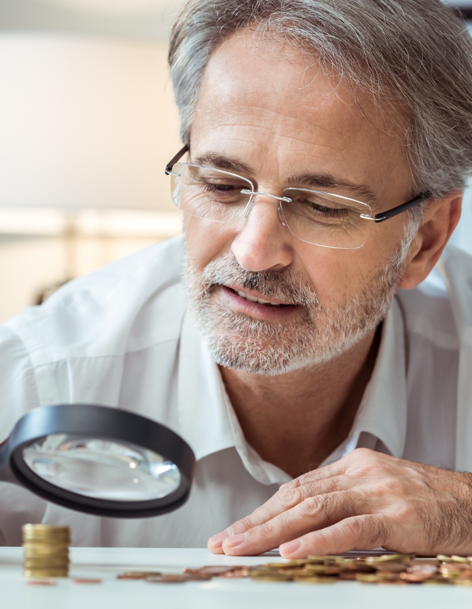 Mann mit Lesebrille und Lupe zählt Kleingeld.