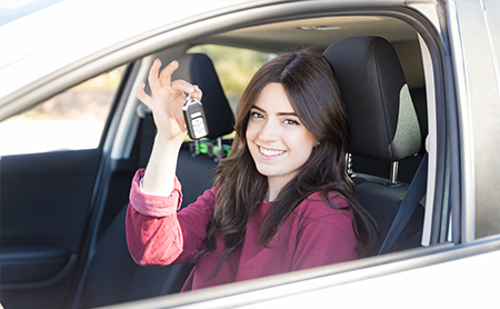 Junge Frau im Auto mit Autoschlüssel in der Hand